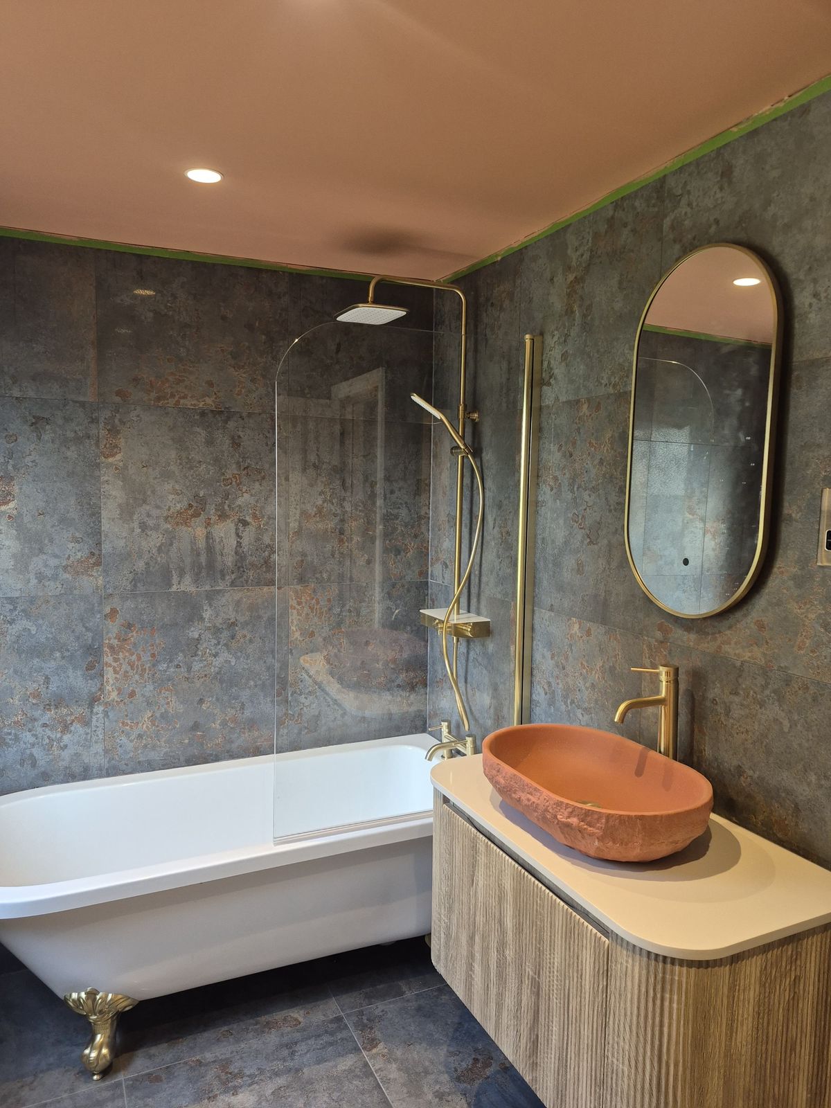 Luxury bathroom installation with stone tiles and brass fittings by BH Refurbs